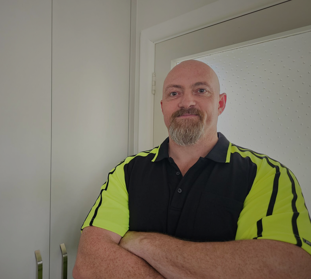 Owner, Morne standing with his arms crossed infront of a cupboard.